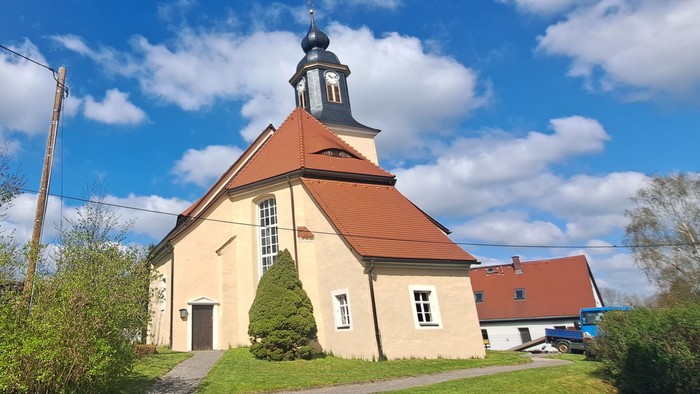 Kleine Kirche mit rotem Dach und Turm unter blauem Himmel