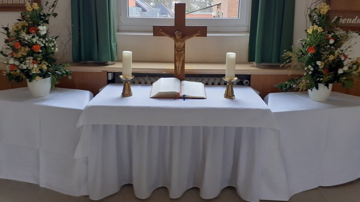 Ein Altar in einer Kirche mit Kreuz, Kerzen und Blumen.