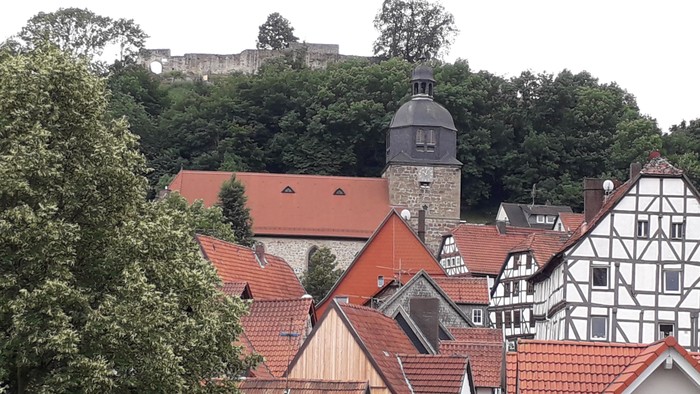 Häuser mit roten Dächern und ein Uhrturm im Hintergrund.