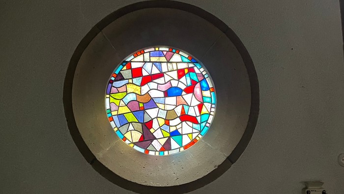 Ein rundes Buntglasfenster an einer weißen Wand.