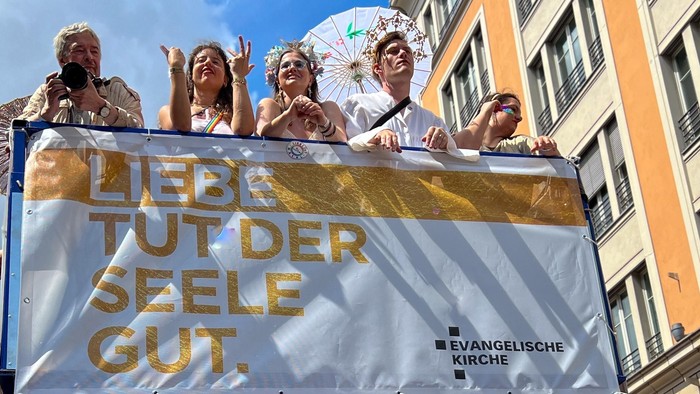 Eine Gruppe von Menschen hält ein Banner mit der Aufschrift "Liebe tut der Seele gut."