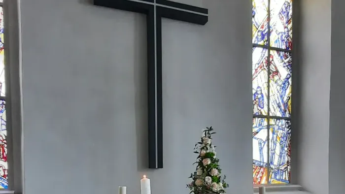 Kircheninneres mit Kreuz, Kerzen und Buntglasfenster