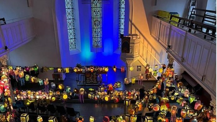 Eine große Kirche mit vielen bunt beleuchteten Kerzen und Menschen.