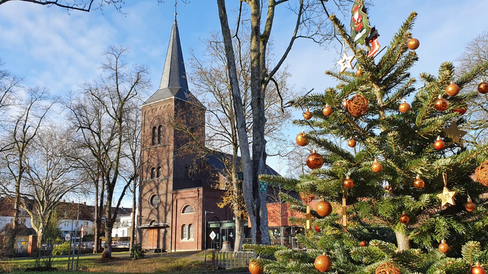 Weihnachtsbaum vor Kirche mit Orangen und Sternen geschmückt