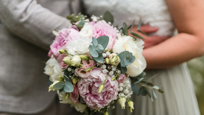 Eine Braut hält einen Strauß aus rosa und weißen Blumen.