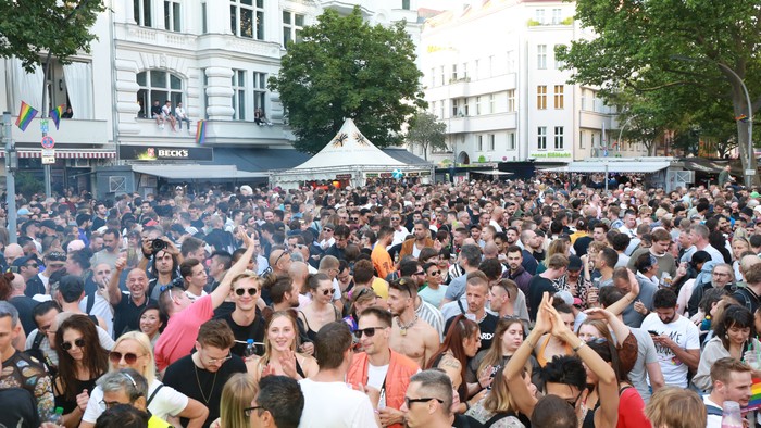 Große Menschenmenge feiert auf belebter Straße mit Gebäuden im Hintergrund