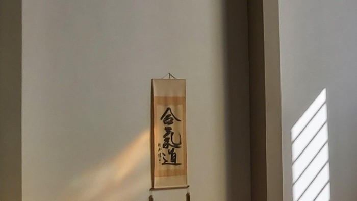 Ein Raum mit einem hängenden Schriftrollenbild und einer Vase auf einem Tisch.