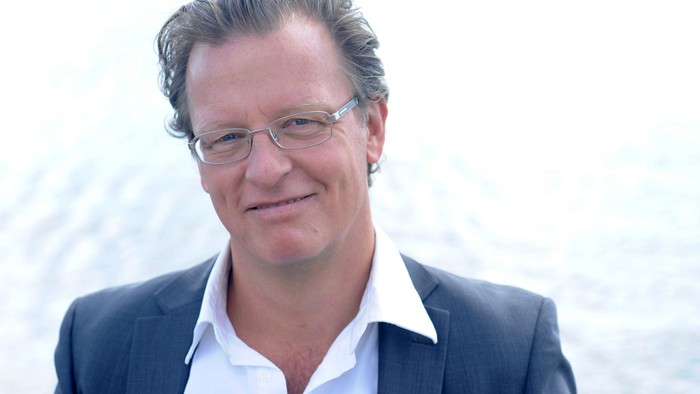 En smilende mand med briller og anzug.