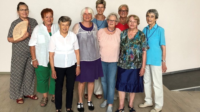 Gruppe von Personen, die vor einem Gemälde posieren.