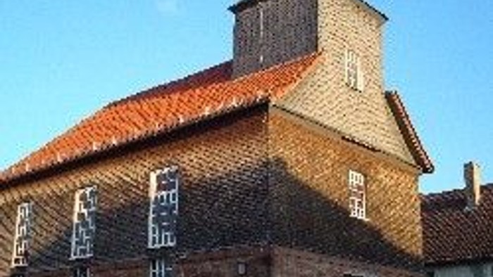 Steinkirche mit rotem Dach und hohem Glockenturm.