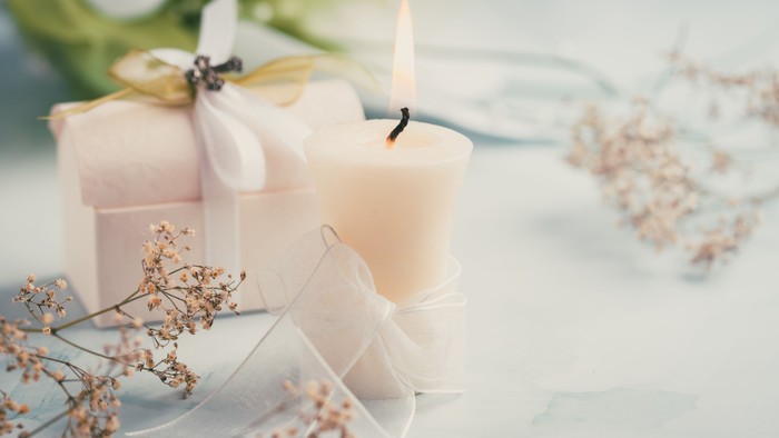 En hvid lysstøbende borddekorationsopstilling med lysende lys, blomster og glas.