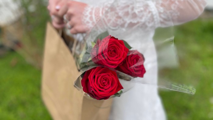 En person holder et papirbundt røseblomsterbuket.