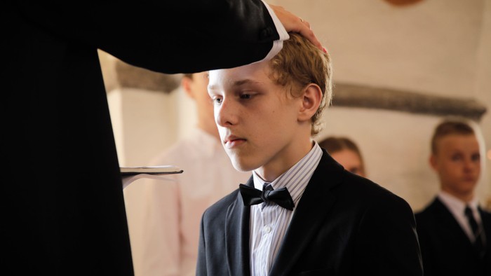 En ung dreng i formel klædning med bomme og hvid skjorte ser opad.