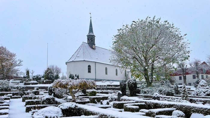 Snødekt kirke og gravlund i et lille bysamfund