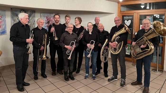 Die Mitglieder des Bläserkreises imHalbkreis mit Instrumenten. Alle tragen schwarze Oberteile und dunkle Hosen.