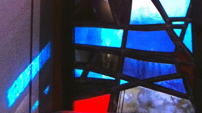Bunte Glasfenster in Kirche mit Kreuz und blauem Himmel