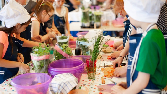 Menschen bereiten gemeinsam an einem Tisch mit verschiedenen Zutaten und Schüsseln Essen zu.