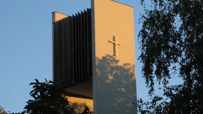 Kirchturm mit Kreuz vor blauem Himmel