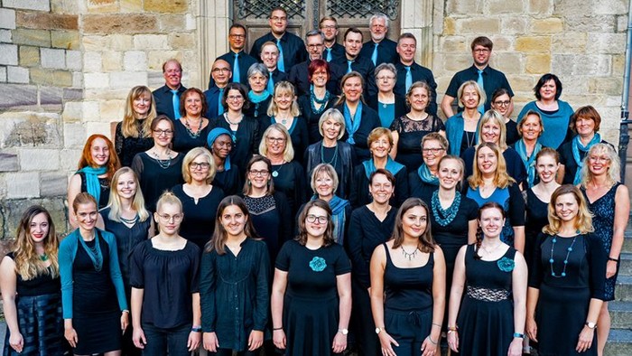 Ein großer Chor posiert vor einem steinernen Gebäude