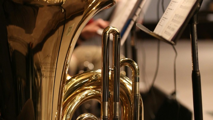 Eine Nahaufnahme einer Tuba mit einem unscharfen Hintergrund, auf dem eine Person sie spielt.
