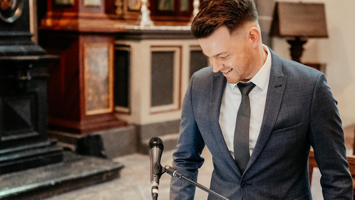 Ein Mann in Anzug spielt Cello in einem eleganten Raum.