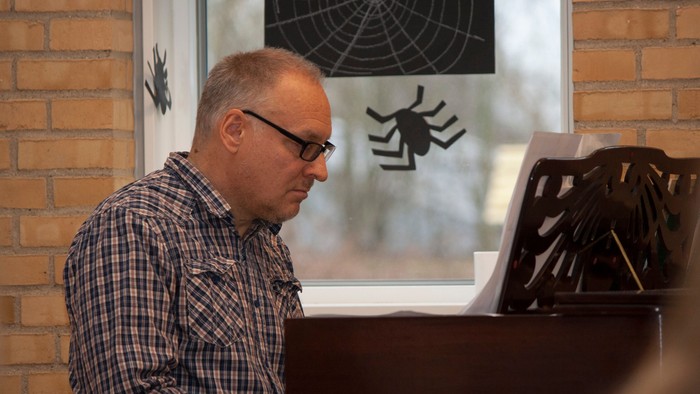 Mand spiller piano ved vinduet