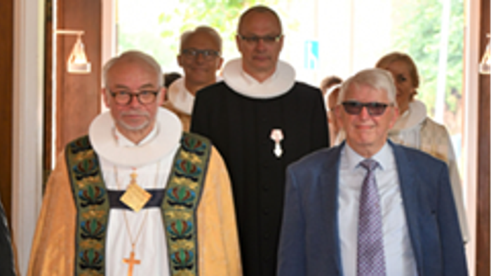 En gruppe mænd, der inkluderer to præster i ritualdrægt, går ind i et bygning.