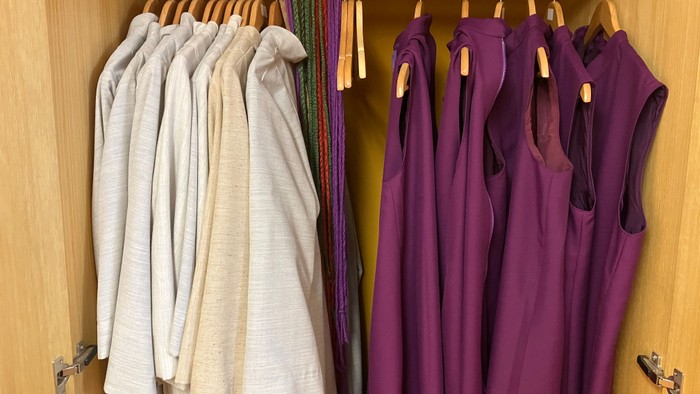 Im Schrank hängen weiße und lila Hemden ordentlich auf Bügeln