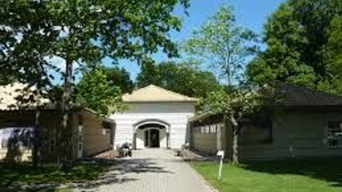 En smuk park med en lang, ret linjet sti og et stort, hvitt portal med en bueformet indgang.