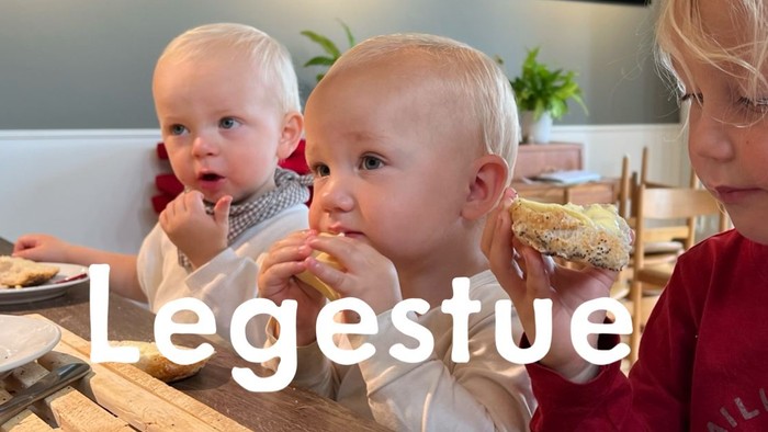 Tre små børn sidder ved bordet og spiser.