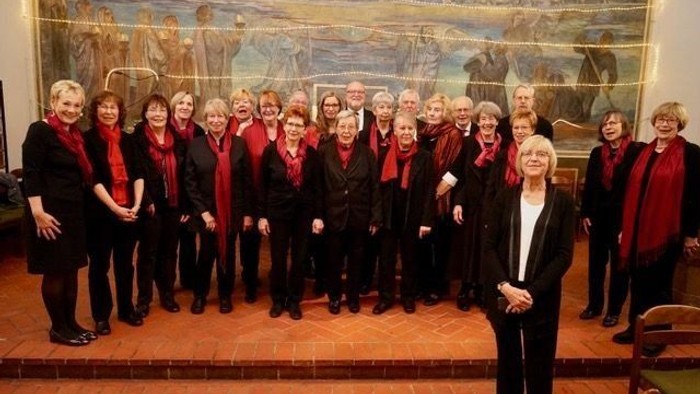 Ein Chor steht vor einem großen Wandgemälde.