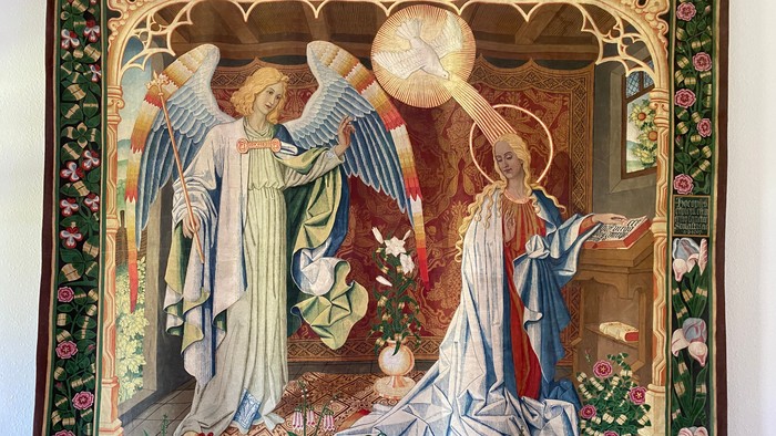 Das Bild zeigt zwei Engel in einem verzierten Rahmen mit Blumen und Text.