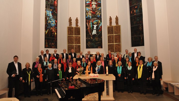 Eine Gruppe von Menschen posiert in einer Kirche vor einem Altar und buntem Kirchenfenster