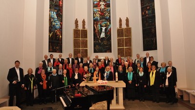 Eine Gruppe von Menschen posiert in einer Kirche vor einem Altar und buntem Kirchenfenster