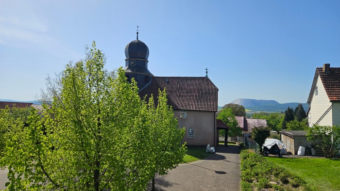 Kirchhof mit altem Gebäude und Bäumen unter klarem Himmel