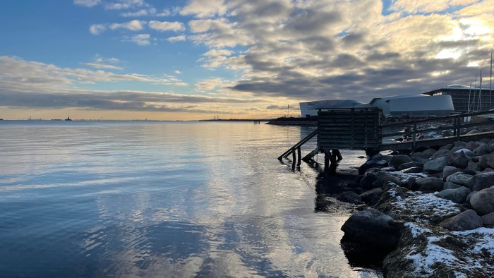 En rolig havnehavn ved solnedgang med en lille kaj og stenstrand