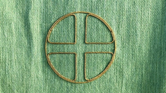 Et rundt symbol med fire linier på grøn stof.