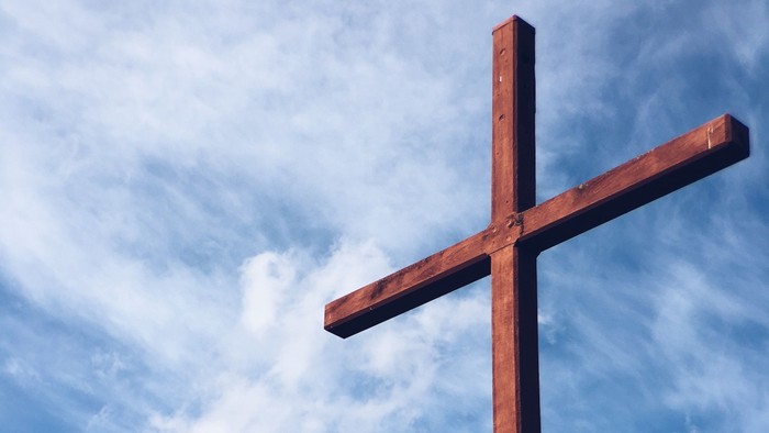 En stor trækorsstand mod en blå himmel med hvidt og grå skyer.