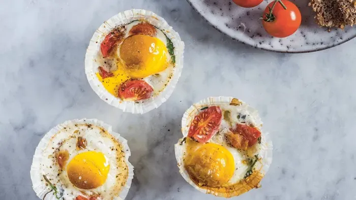 Three ægkupler med grønne og røde tomater på marmoroverflade