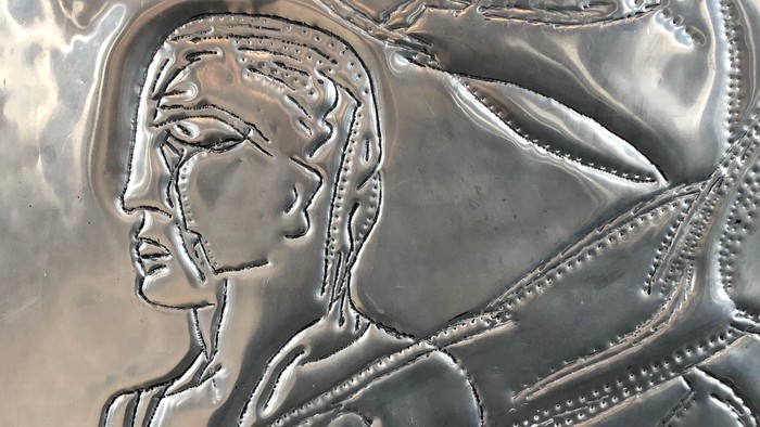 Det er en relief af en kvinde med hånd på hjerte.