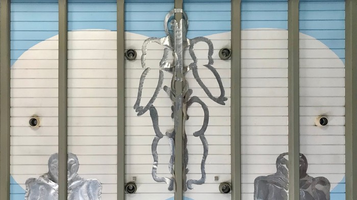 Billedet viser tre panelet med blå himmel og skyer, med et centralt motiv af en stiliseret træ og to figurer.