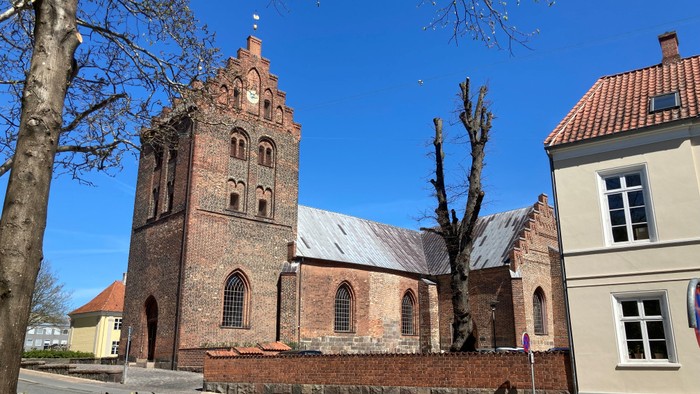 Gamle kirke ved vej med træer og andre bygninger