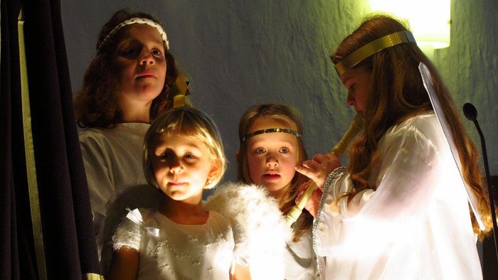 Vier Mädchen in weißen Kleidern mit Kopfbändern posieren für ein Foto