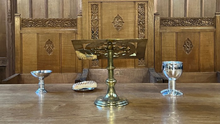 Wooden church interior with ornate paneling and brass items on table