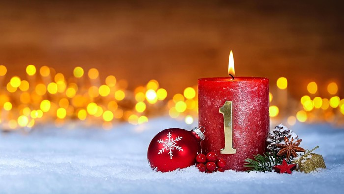 A red candle with the number one, surrounded by holiday decorations and lights.