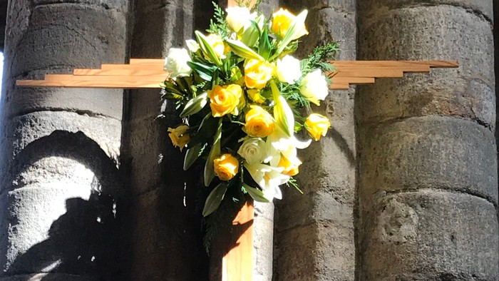 Cross with flowers against stone wall