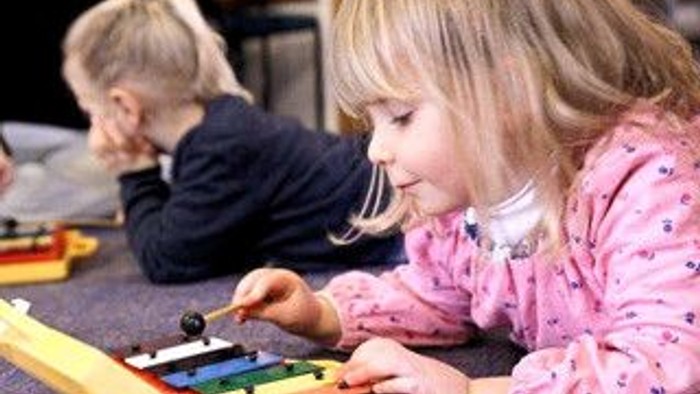 To børn spiller med legetøj på guldtæppe.