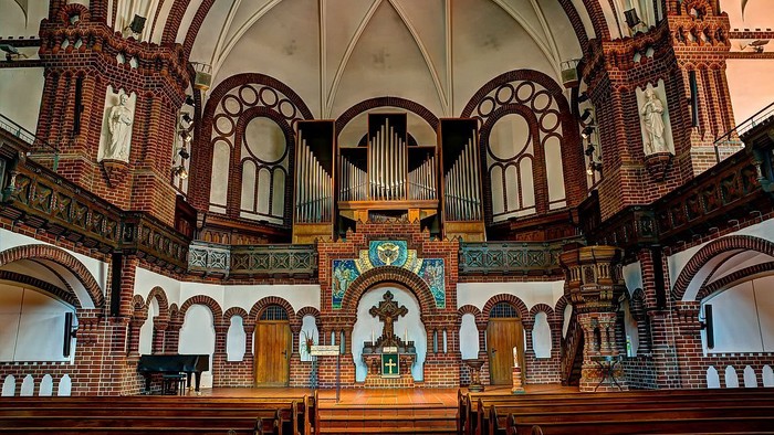 Innenraum einer Kirche mit Orgel und Buntglasfenstern