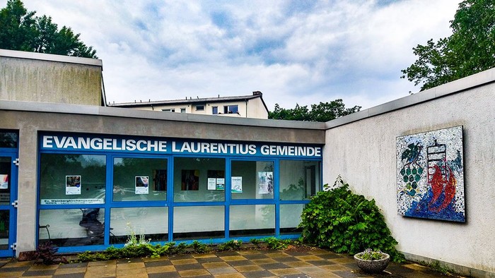 Evangelische Laurentius Gemeinde Gebäude mit farbenfrohem Mosaik und Pflanzen.