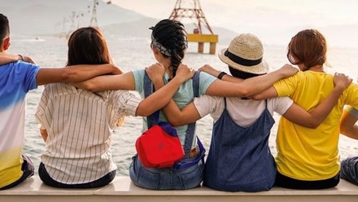 Eine Gruppe von Menschen sitzt mit dem Rücken zur Kamera und schaut auf das Meer.